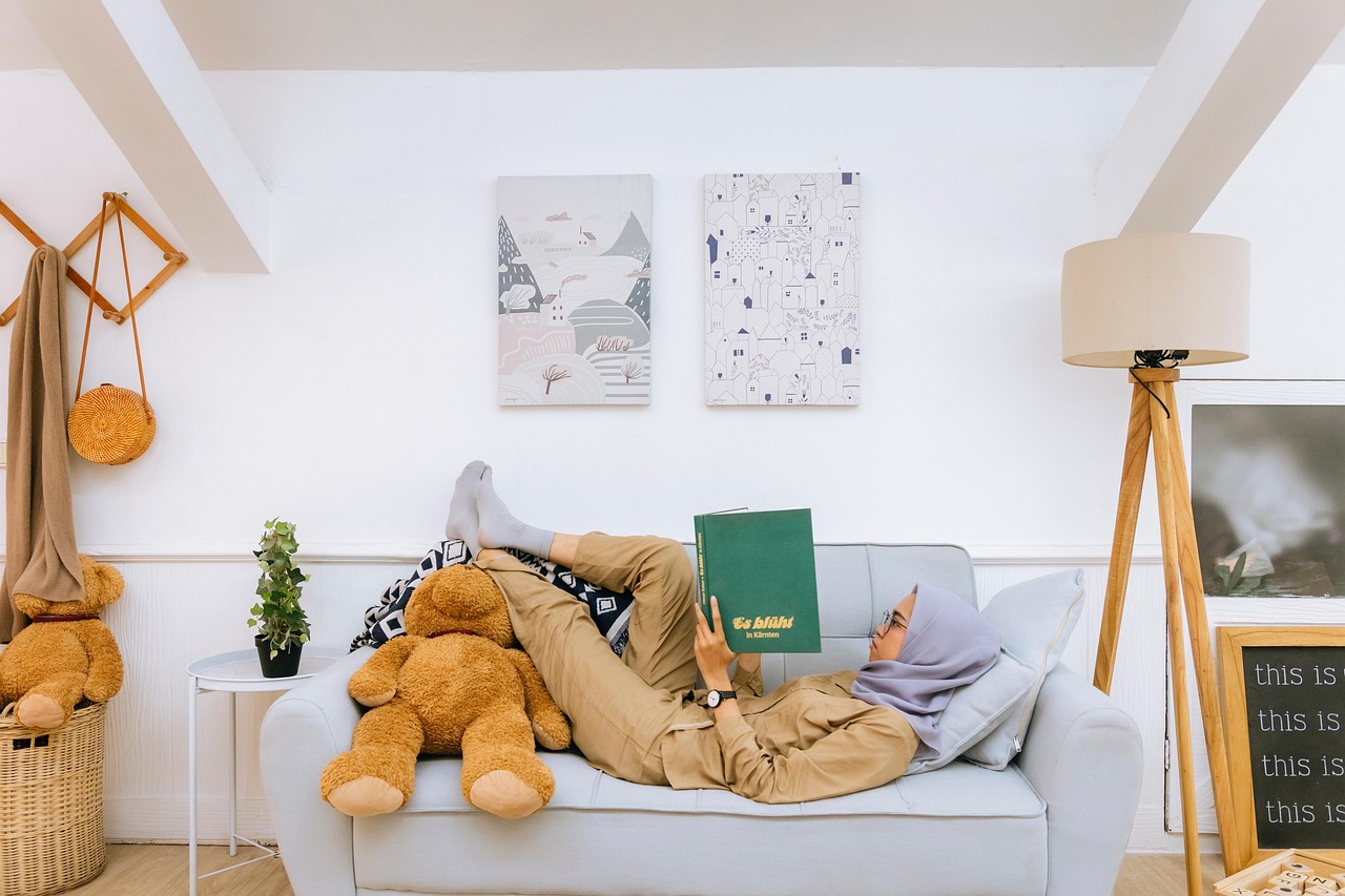 Zelfzorg bij levend verlies: vrouw met hoofddoek, ligt ontspannen op een rommelige bank een boek te lezen