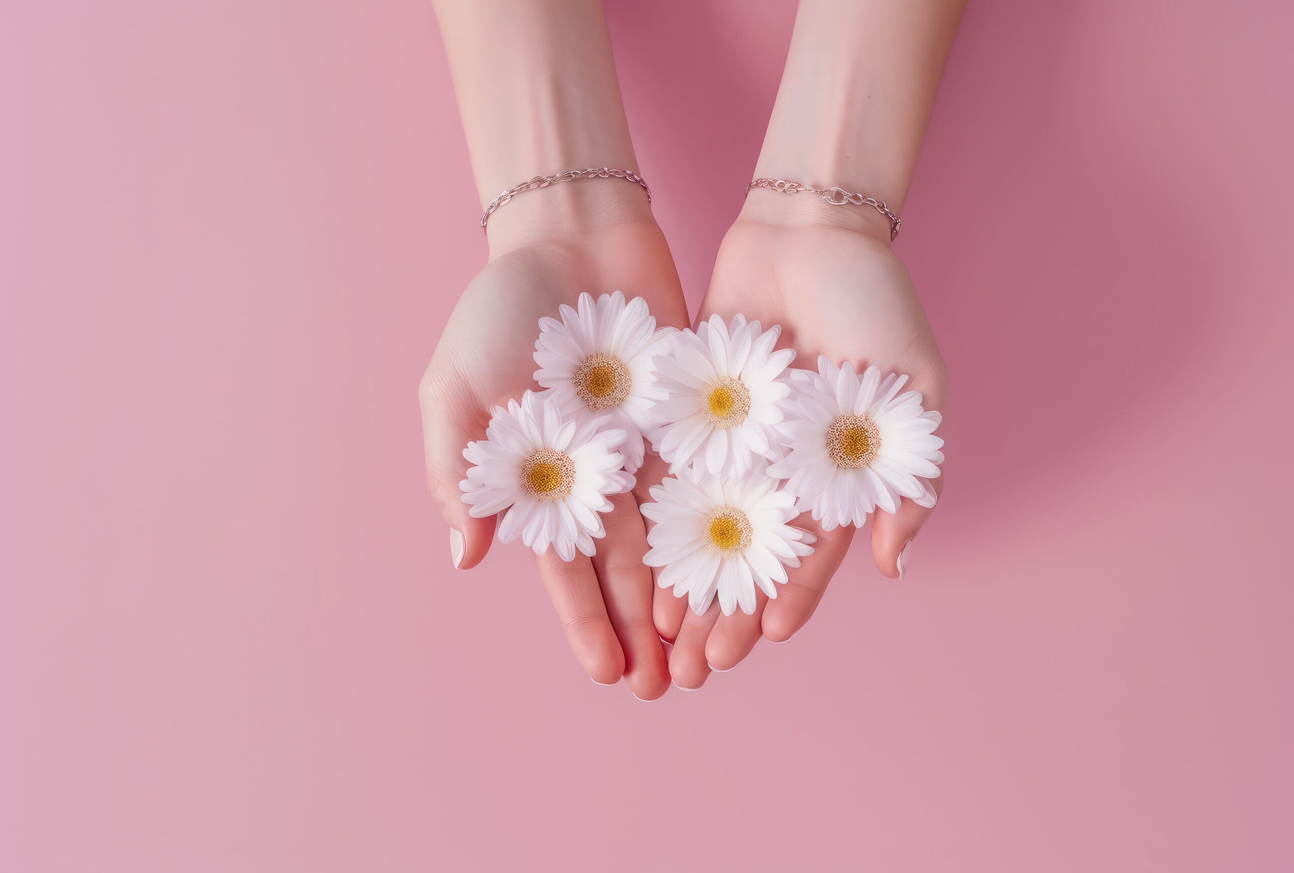 Operatie carpaletunnelsyndroom: opengevouwen handen van een vrouw met witte bloemen erin op een rose achtergrond. Je kunt de polsen, waar de carpaletunnel zit, zien.