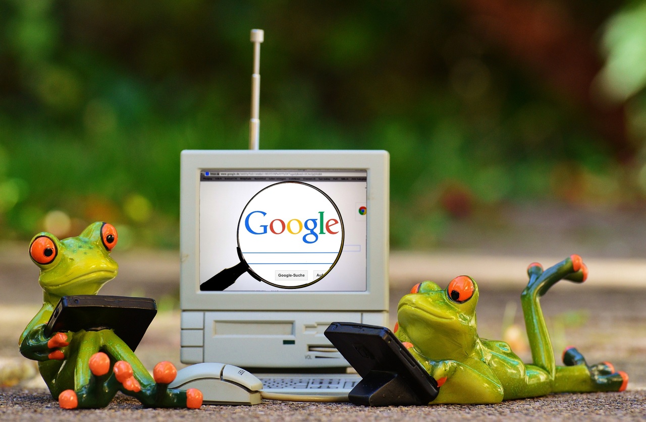 AI: animatie van ouderwetse computer met op het scherm "Google" door een vergrootglas. Eromheen twee kikkers met laptop.