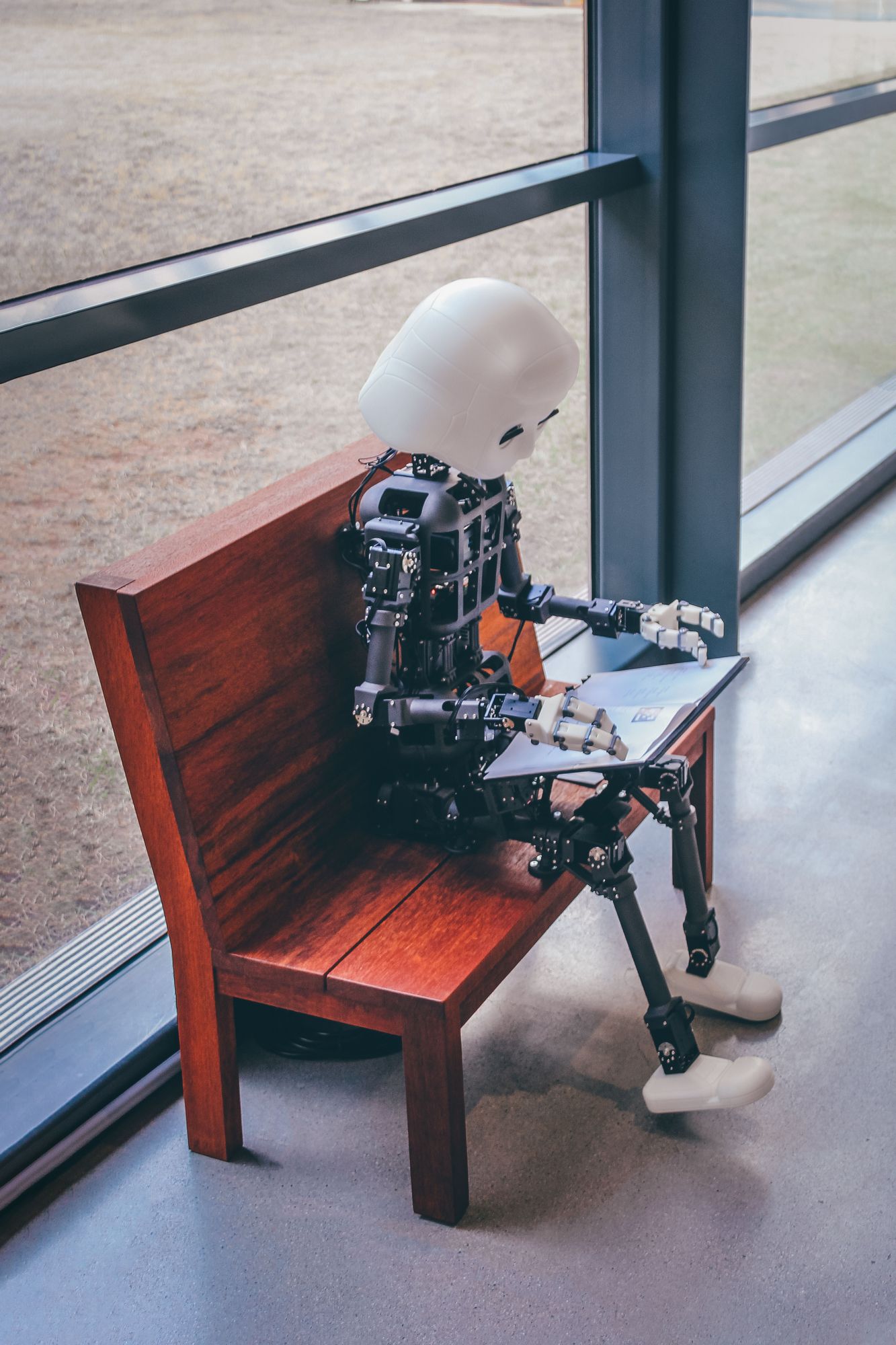 Ervaringsverhaal: AI, robot zit met laptop op een bankje te werken.