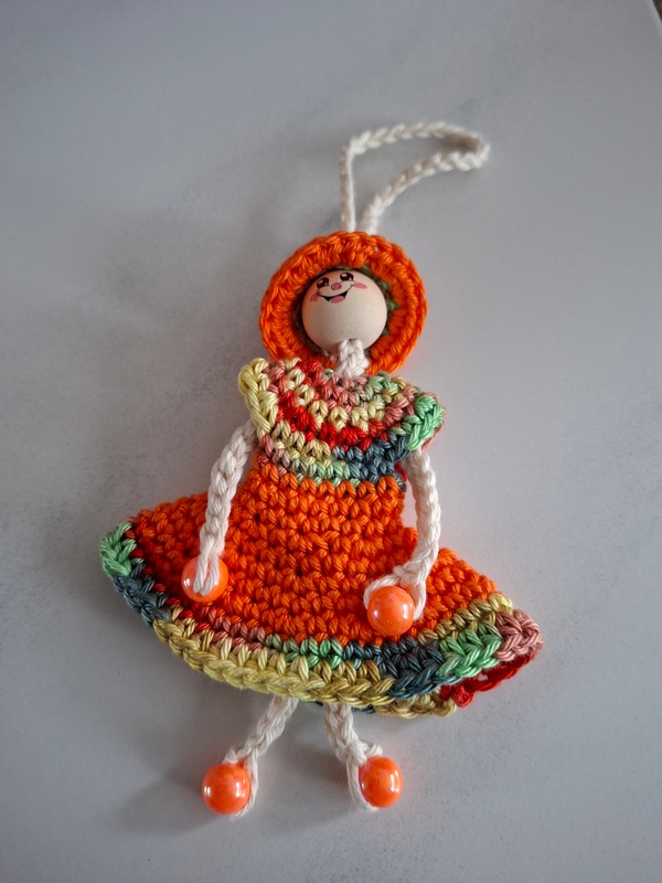 De Overburen, poppetje met jurkje in oranje met rood en groen