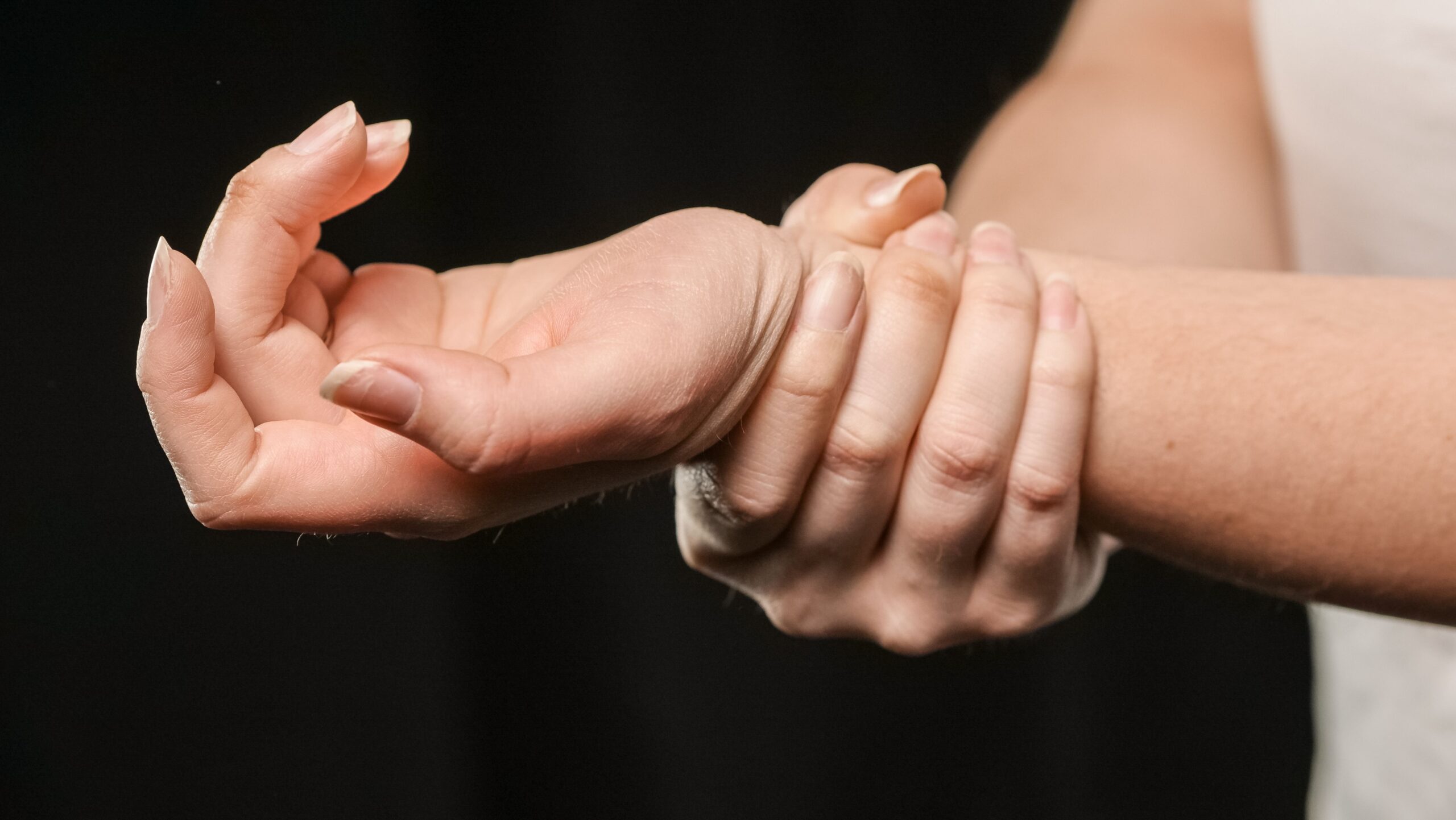Oefeningen carpaletunnelsyndroom: iemand grijpt zijn of haar pijnlijke pols vast.